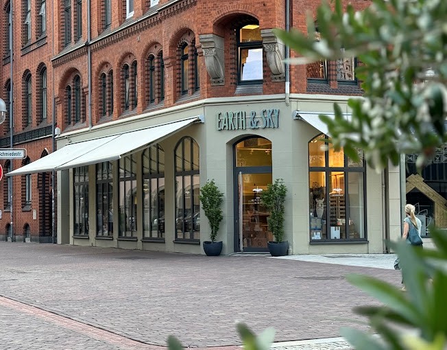 Eckladen „Earth & Sky“ mit großen Fenstern und Markisen in einem roten Backsteingebäude in der Innenstadt.