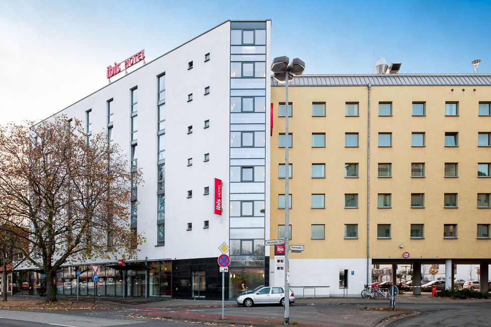 Fassade des Ibis Hotels Hannover City mit weißem und gelbem Gebäudeteil an einer Straßenecke.