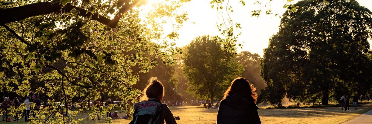 Radfahren in Hannover Zwei Radfahrerinnen bei Sonnenuntergang auf einem Parkweg, umgeben von Bäumen und warmem Licht.