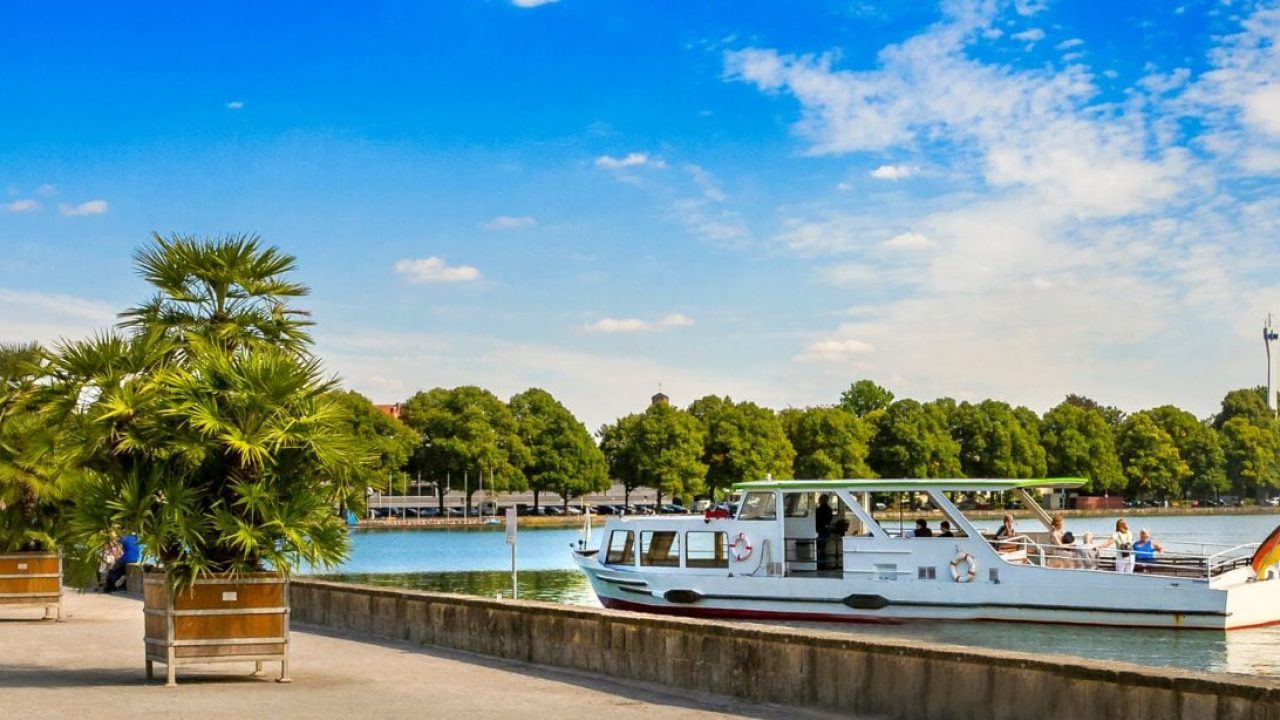 Weiße Ausflugsfähre auf dem Maschsee in Hannover, rechts ein hoher Wasserfontänenbrunnen.